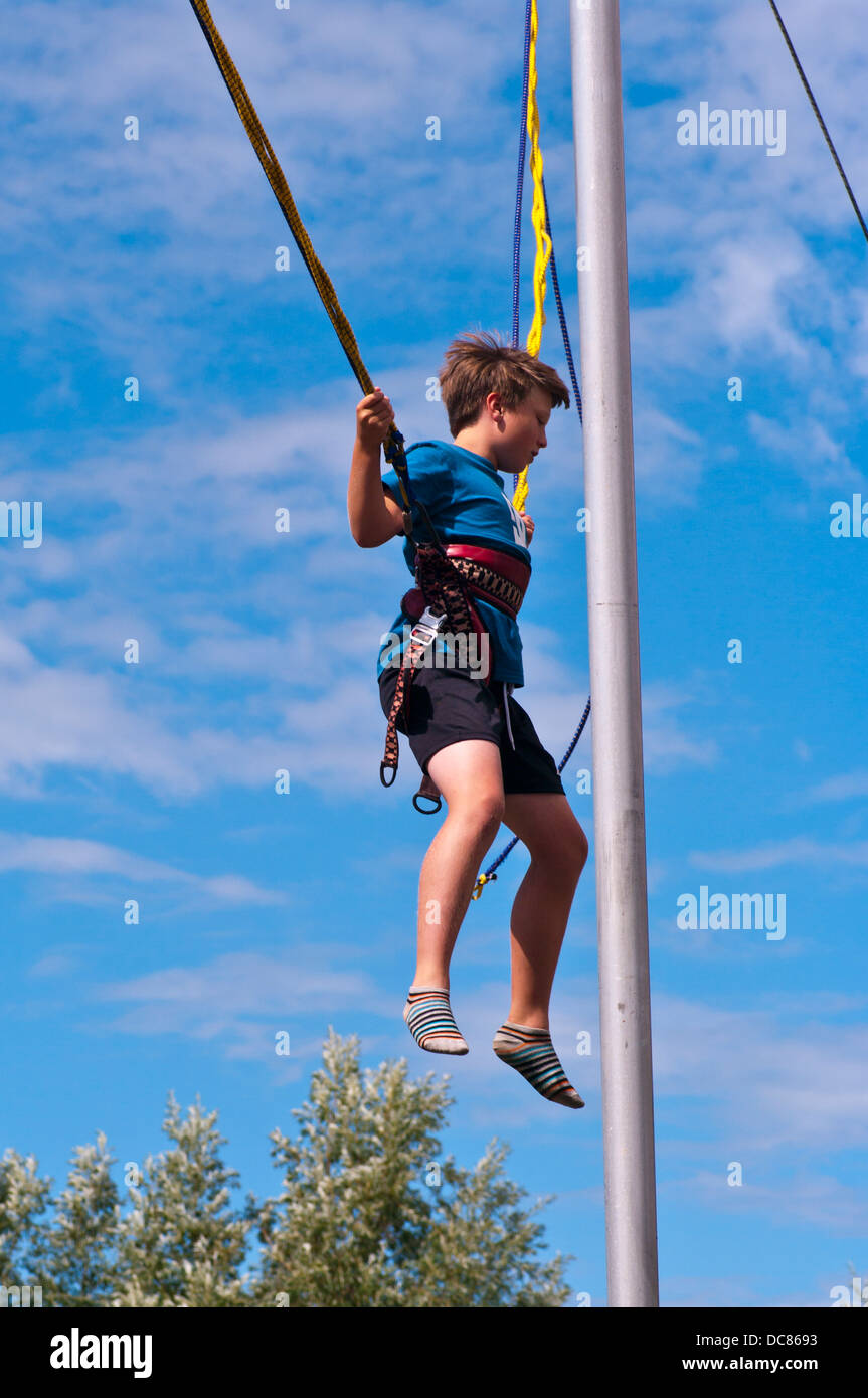 Young Boy Having Fun In The Sun Bouncing On Bungee Ropes Stock Photo