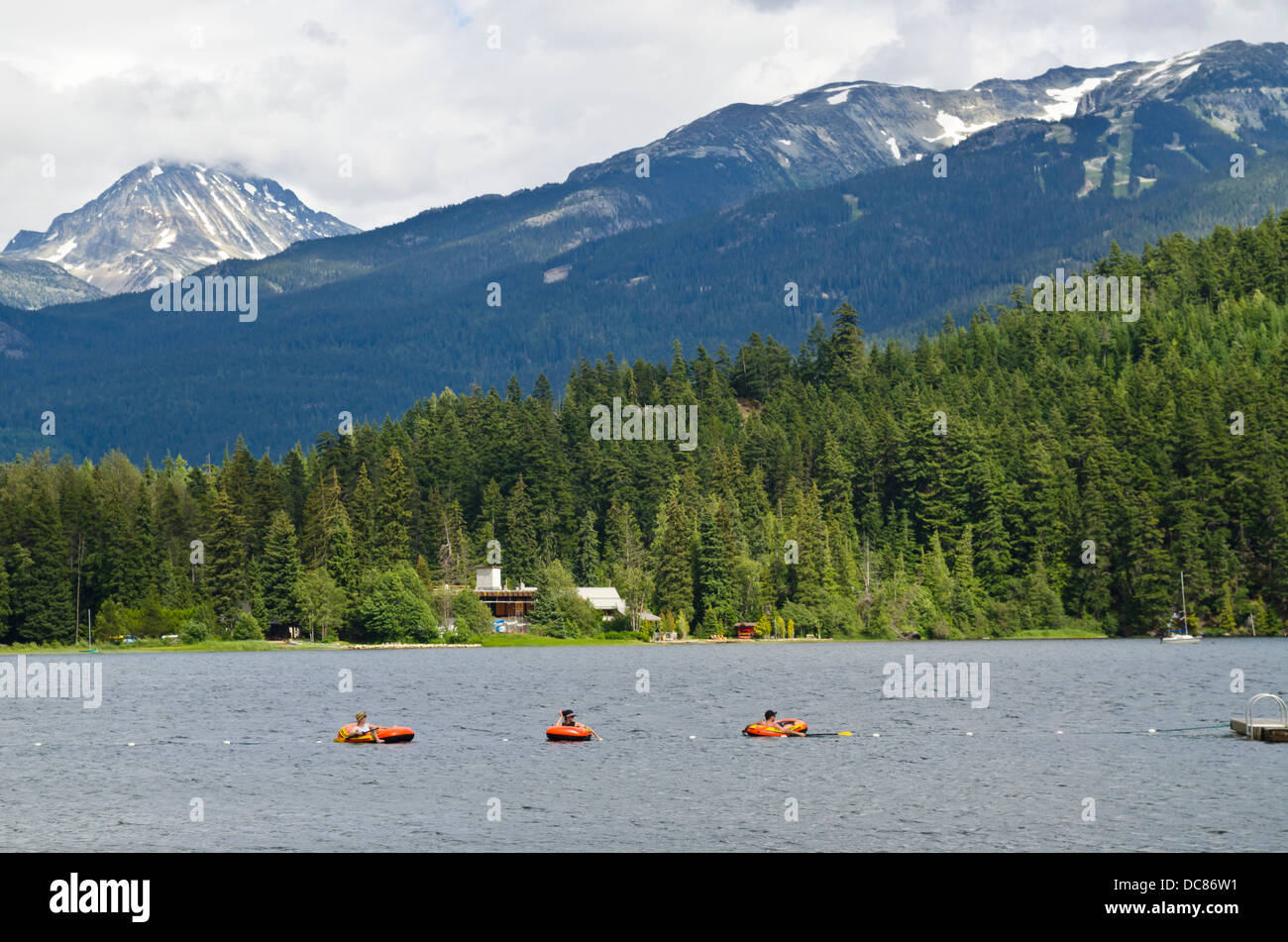 People having fun floating on on Alta Lake in Whistler, BC, Canada, in the summer. Mountains and forest in the background. Stock Photo