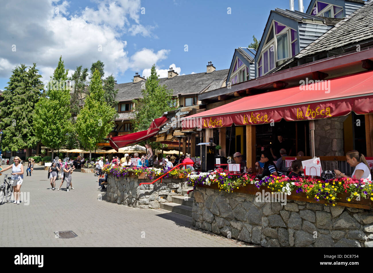 People walking and dining in Whistler village in the summer.  People eating at cafés on patios. In Whistler, British Columbia. Stock Photo