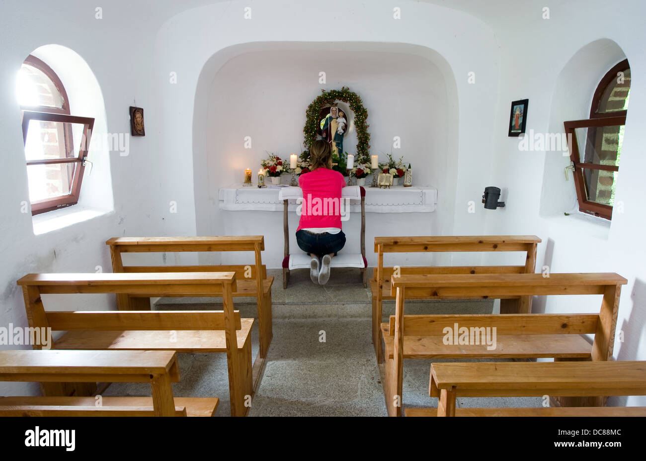 A woman is praying in a small chapel Stock Photo