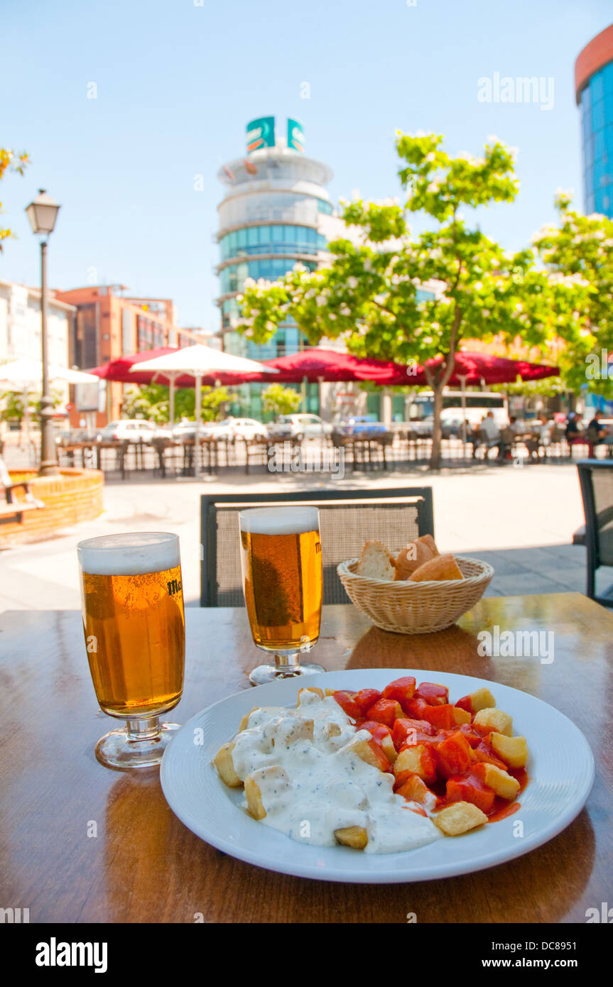 Spanish appetizer: Alioli and Bravas potatoes with two glasses of lager in a summer terrace. Madrid, Spain. Stock Photo