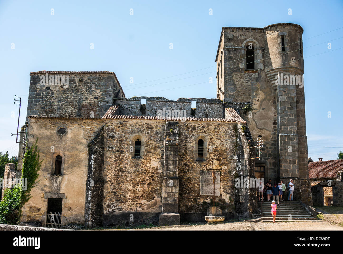 Side of the church, with visitors exiting, in the ruins of Oradour-sur-Glane village, Haute-Vienne department, Limousin, west-central France, Europe. Stock Photo