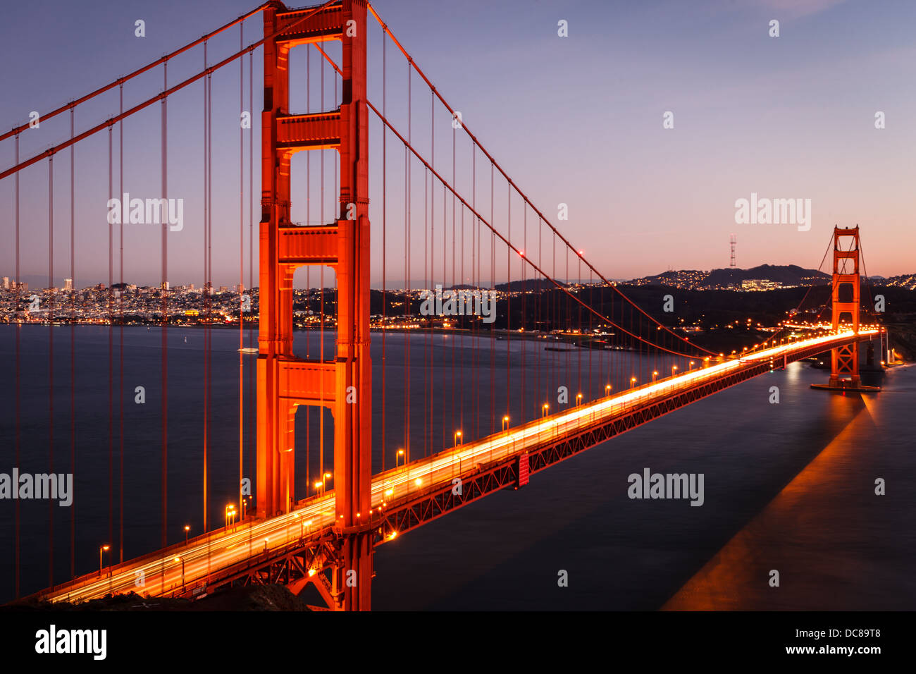 Close-up of the Golden Gate Bridge and city skyline illuminated at twilight in San Francisco aerial view from north side cliffs Stock Photo