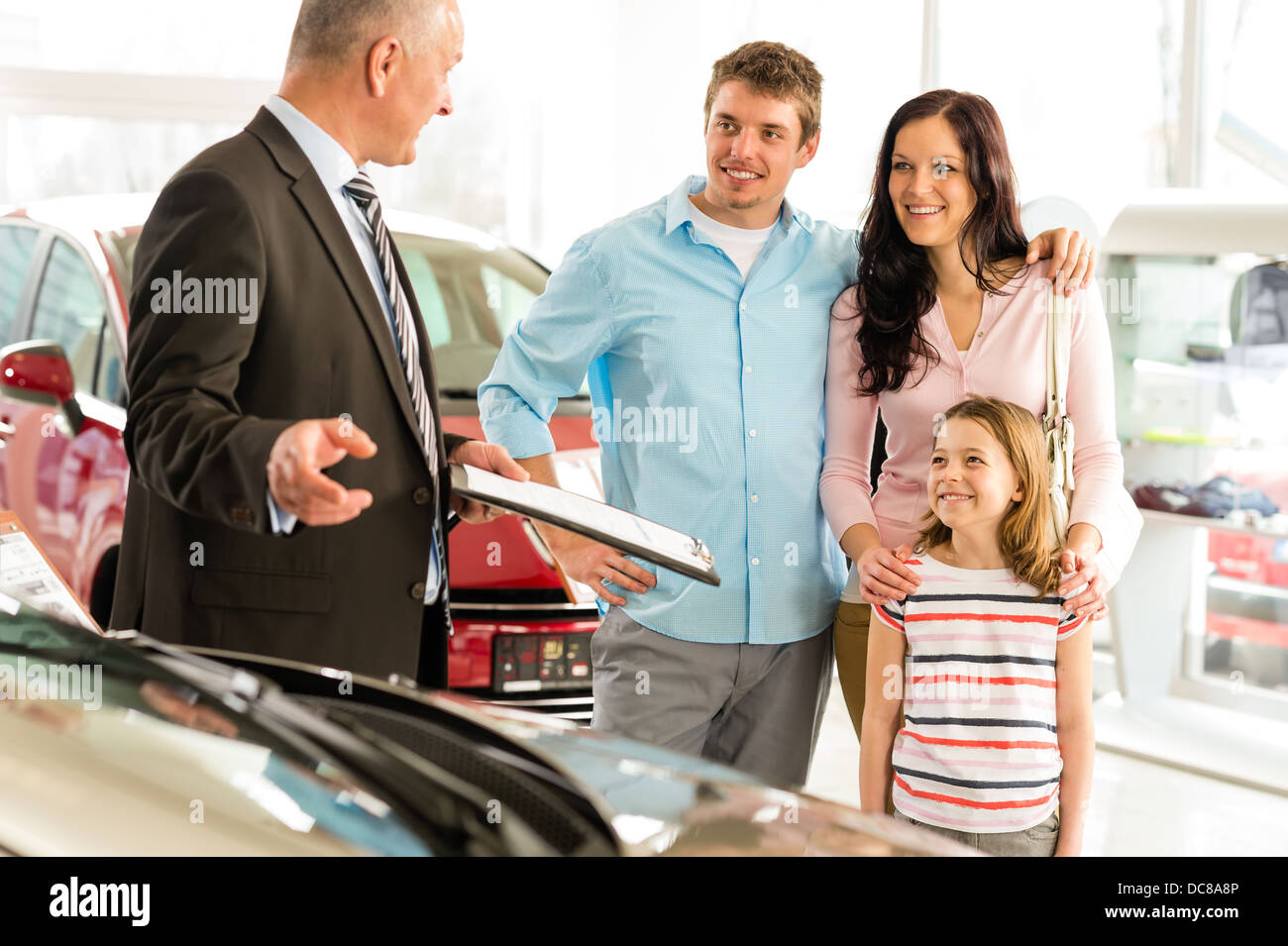 Car dealer offering a car to smiling family Stock Photo