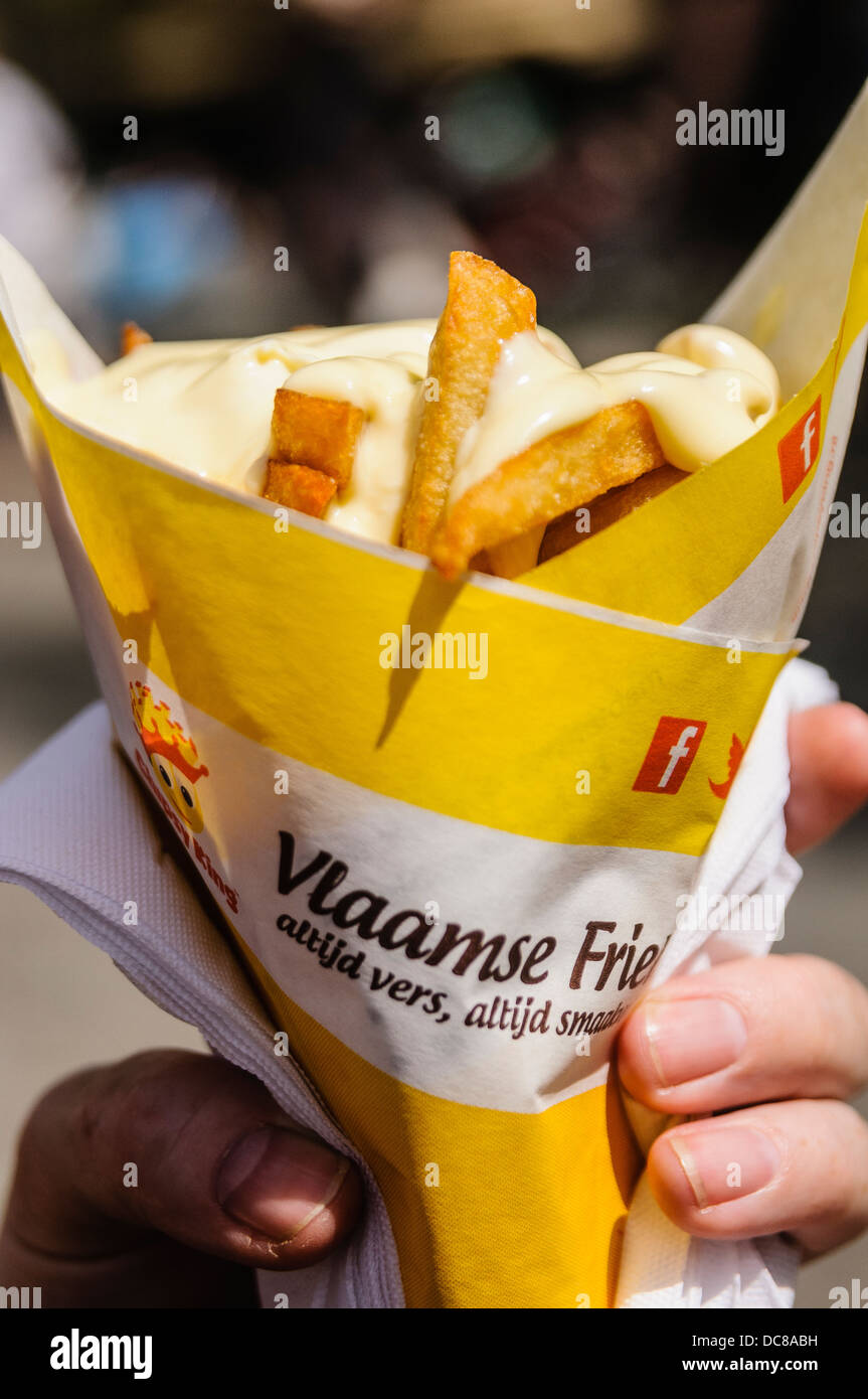 A person holds a cone of fries (chips) with mayonnaise from a Dutch