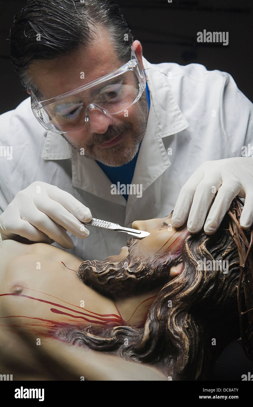 Professional Restorer with a scalpel repairing a sculpture of the crucified Christ, Andalusia, Spain Stock Photo