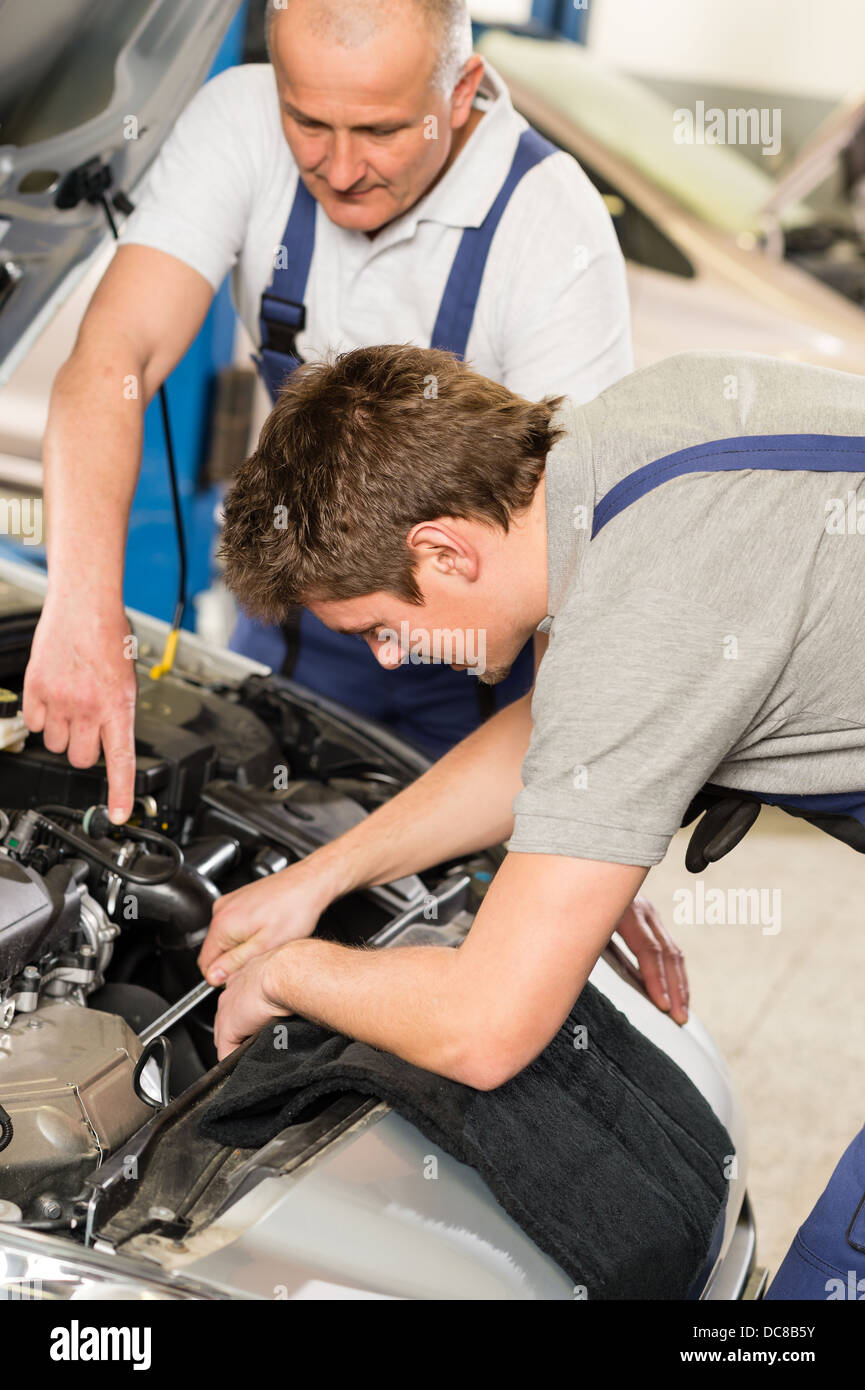 Middle aged car repairman helping colleague in garage Stock Photo