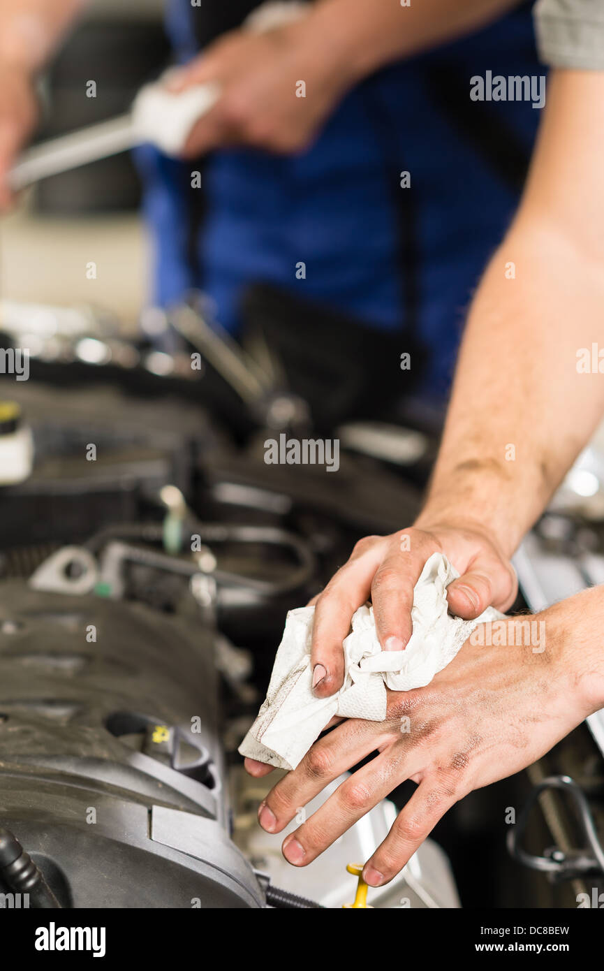 Car mechanic wiping his dirty hands with cloth Stock Photo
