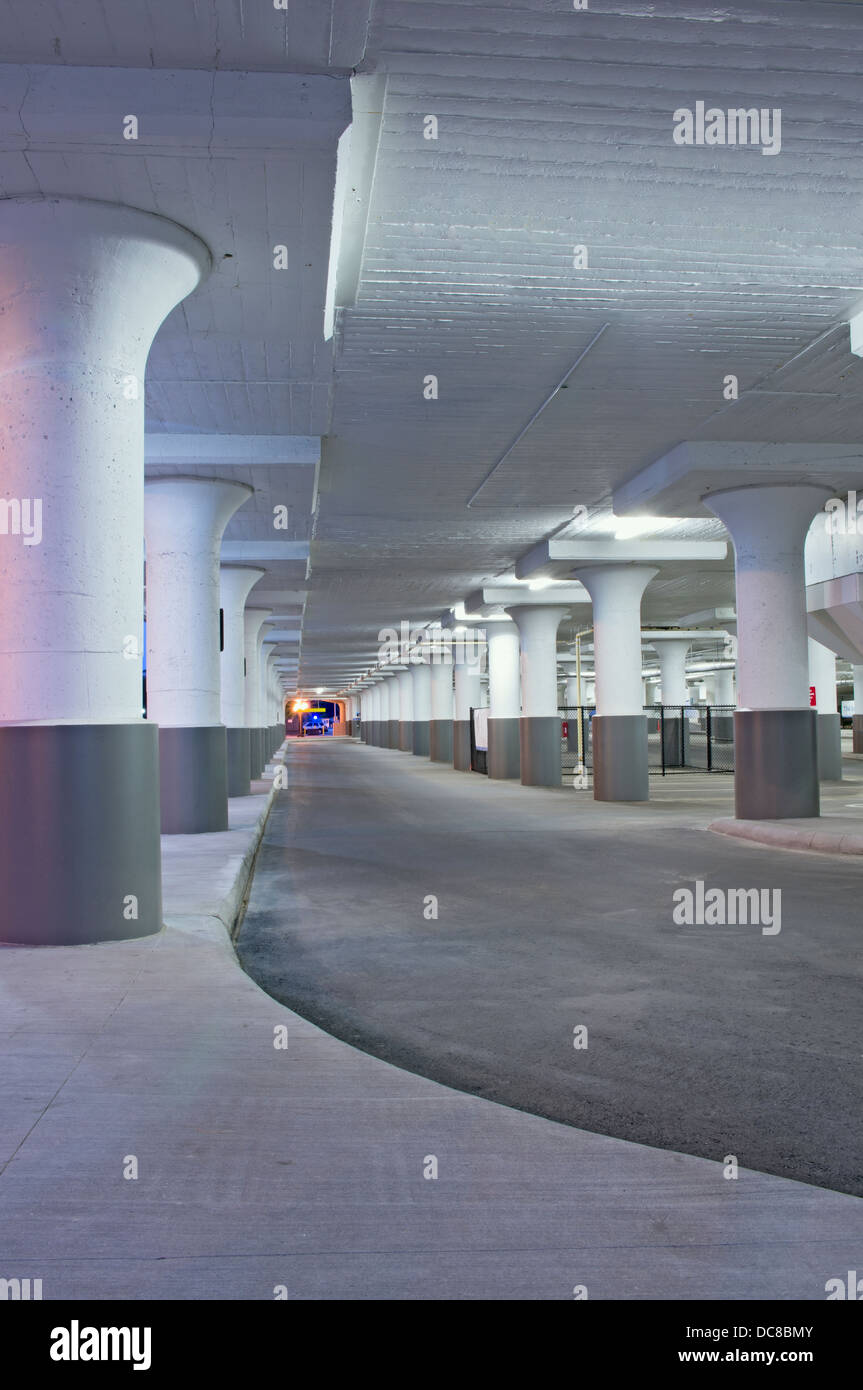 Lower level of parking garage interior illuminated at night Stock Photo