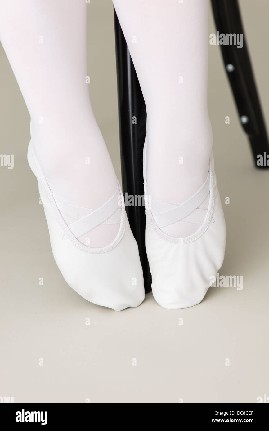 Feet of ballerina wearing white ballet slippers Stock Photo