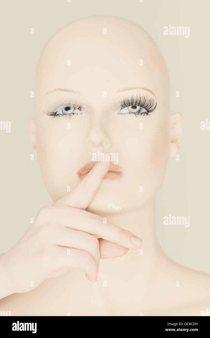 Head of mannequin with human hand covering the mouth Stock Photo