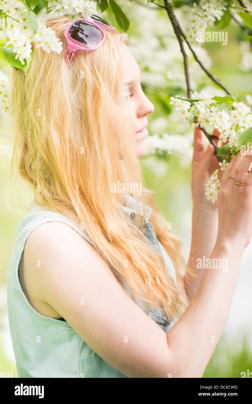 Nature scene with one young attractive woman by a tree in blossom Stock Photo
