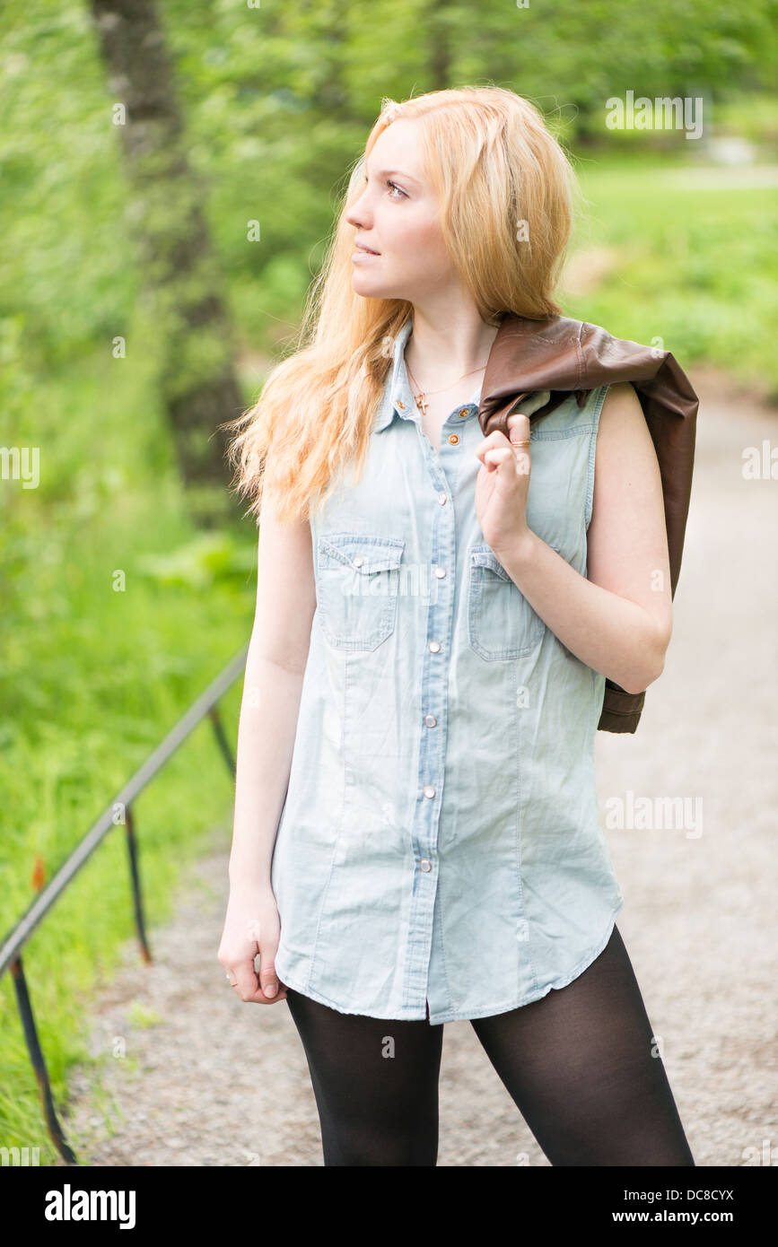 Nature scene with one young attractive woman standing in a park at summertime Stock Photo