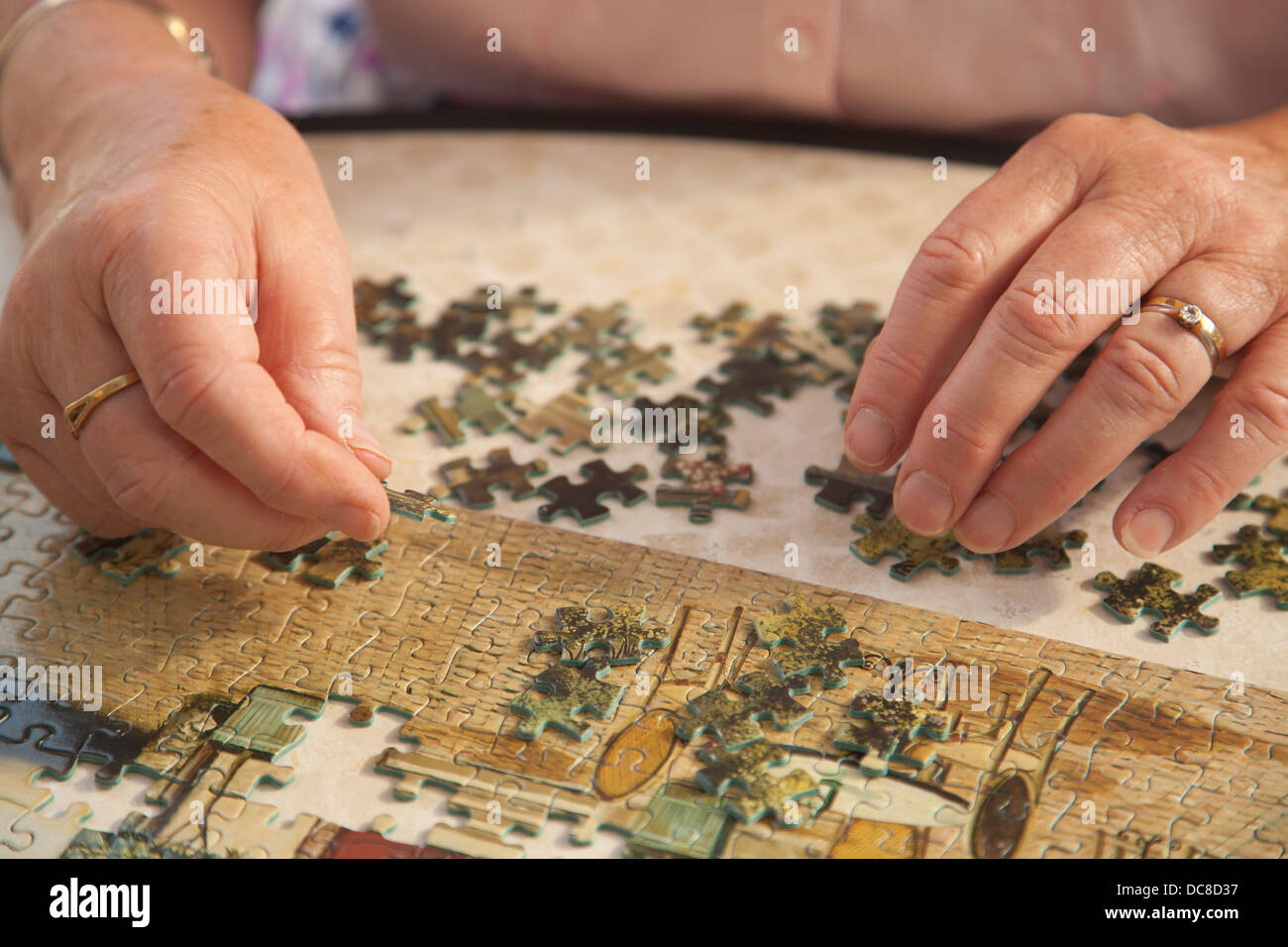 Retired woman making a jigsaw puzzle in her conservatory whilst enjoying a modest standard of living in England, United Kingdom Stock Photo