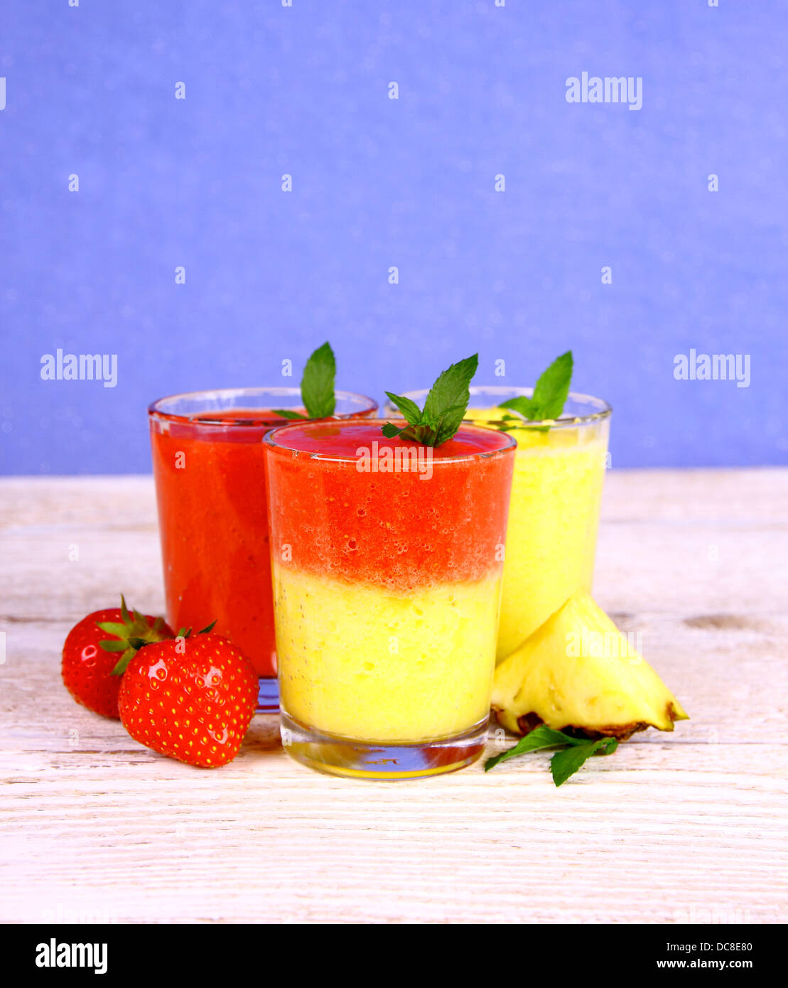 Strawberry and pineapple smoothie mixed on blue background, close up Stock Photo