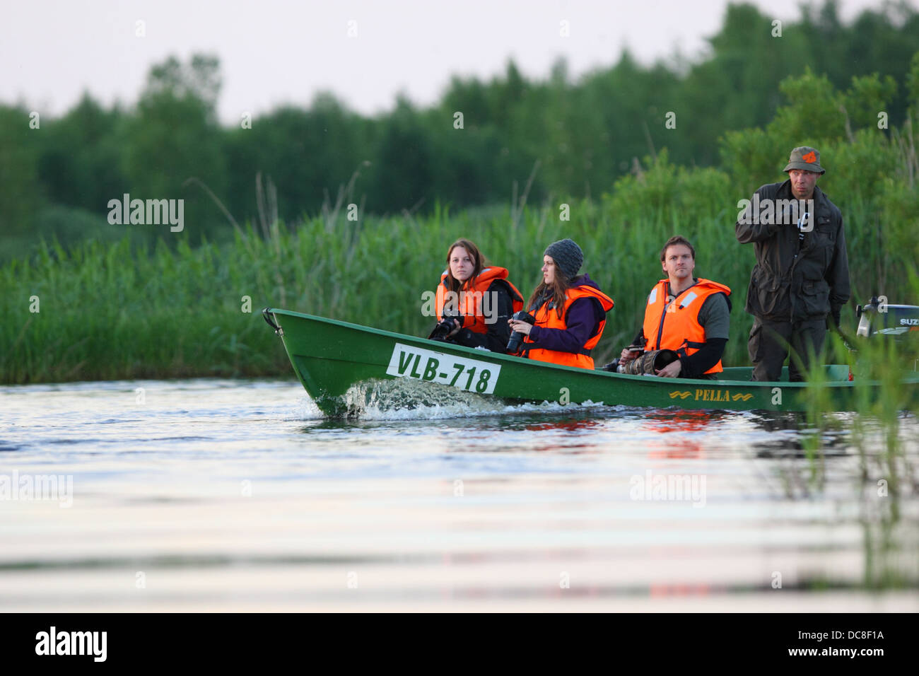 Group of wildlife photographers taking a boat ride, looking for beavers. Europe, Estonia, Alam-Pedja Nature Reserve. Stock Photo