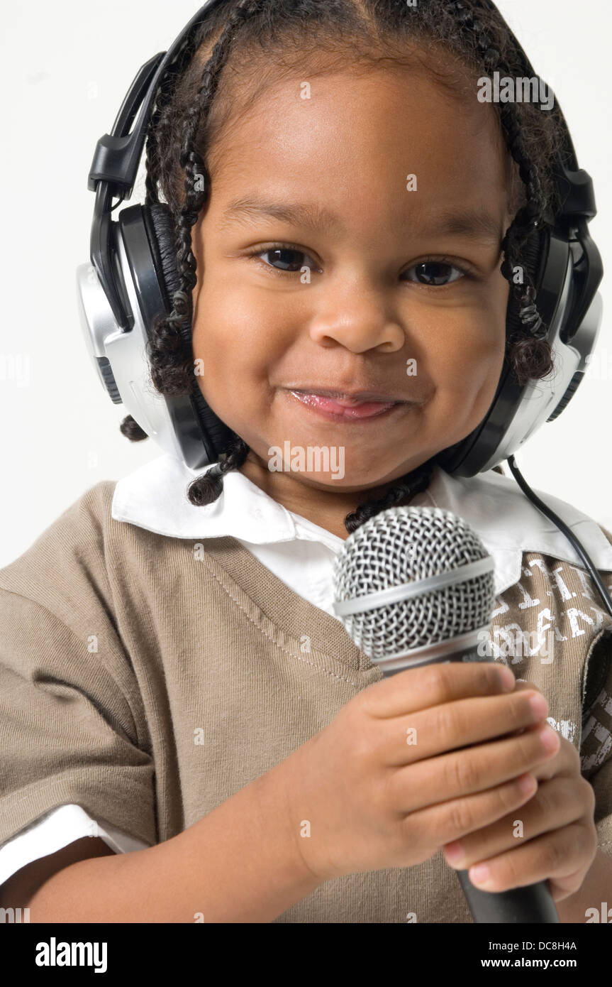 Toddler holding microphone with headphones on head Stock Photo Alamy