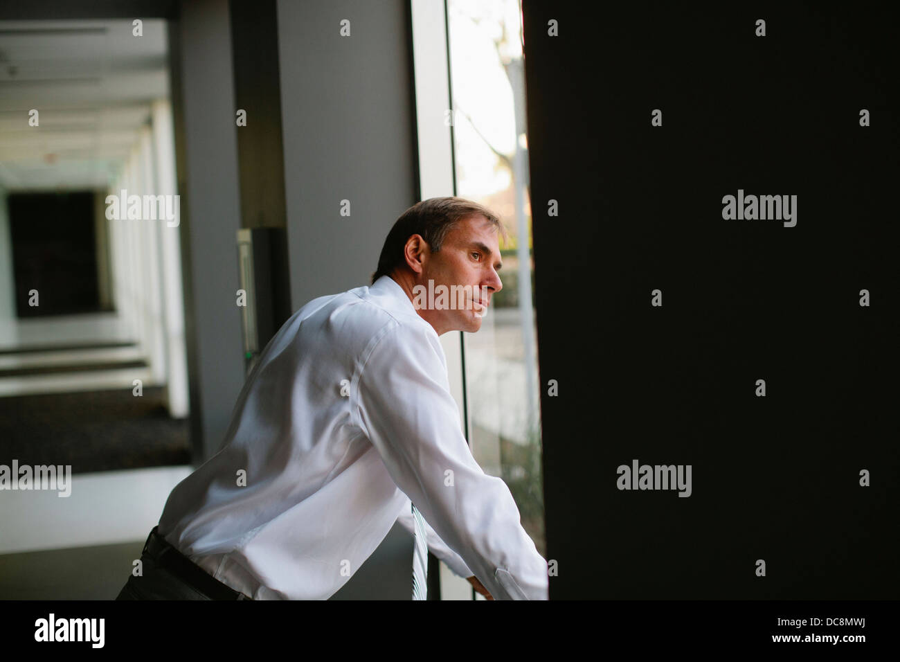 Businessman glances through the window in his office. Stock Photo