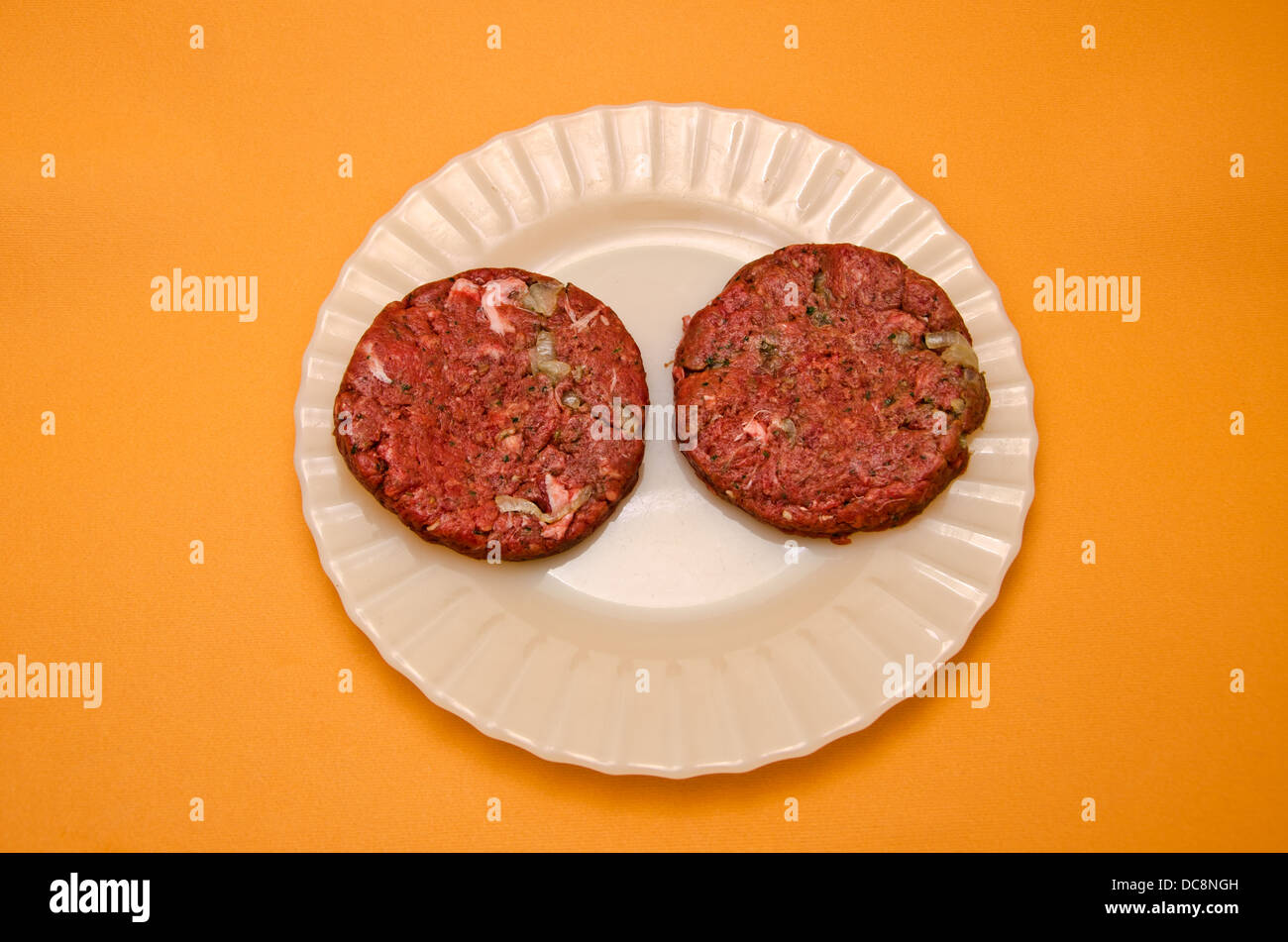 Dish with raw hamburgers Stock Photo