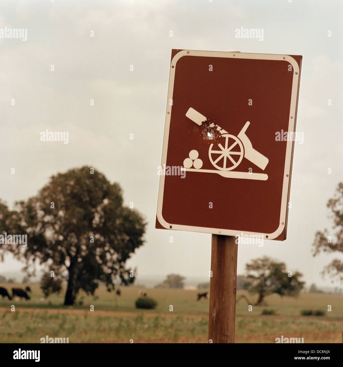 South Africa, Koppies, 2009. A heritage site signpost has a bullet hole through a canon image. Stock Photo