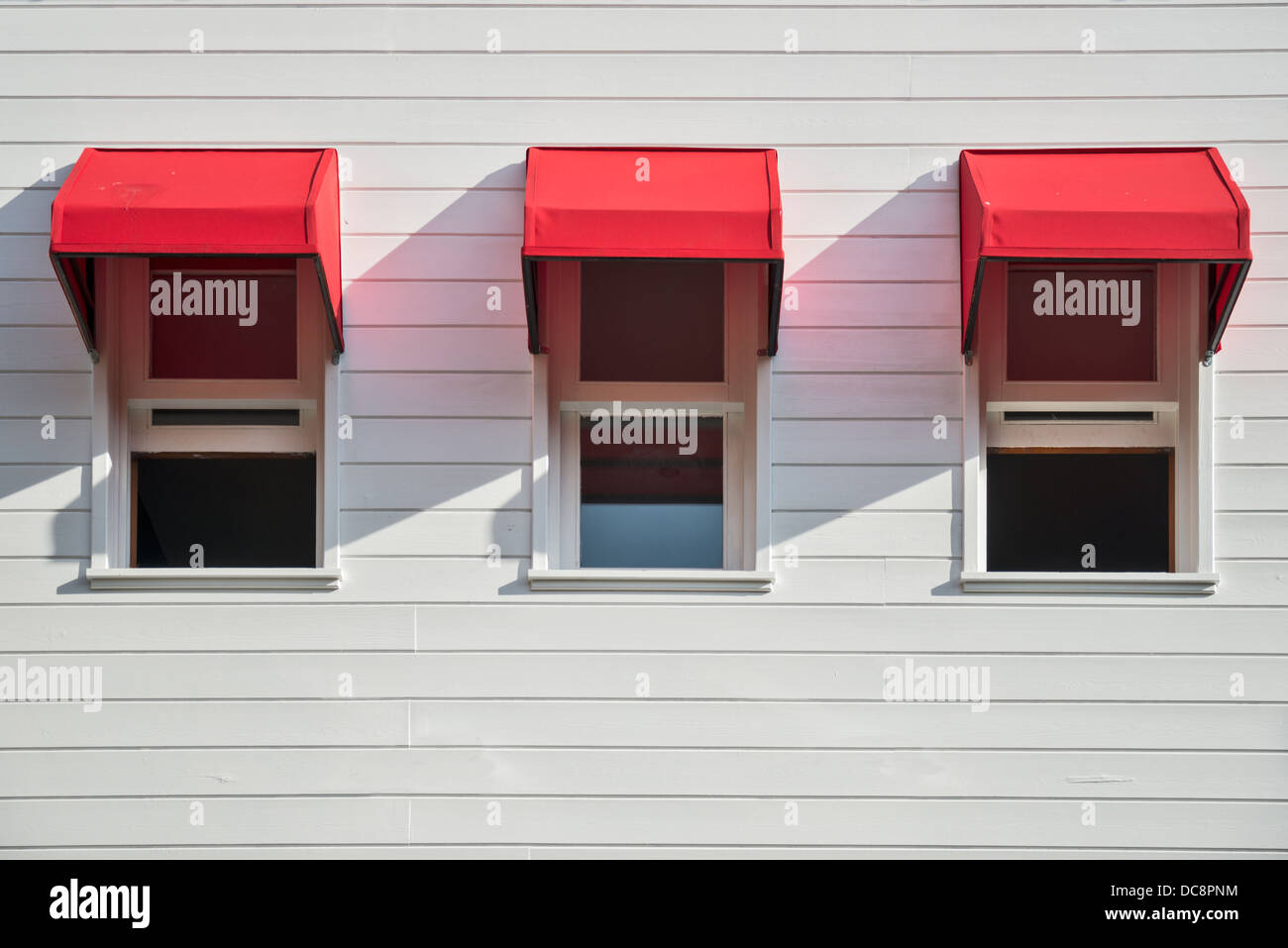 Windows with red shades on a white walled house Stock Photo