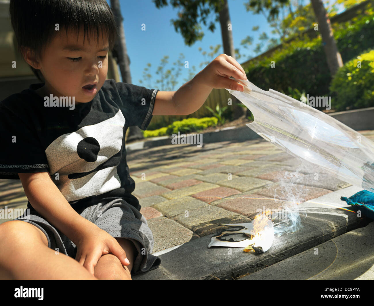 Kid making fire with a magnifying glass Stock Photo Alamy