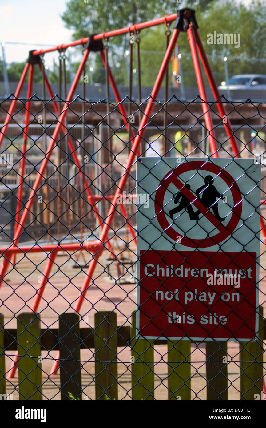 'Children must not play on this site' safety sign attached to a fence outside a children's playground. Stock Photo