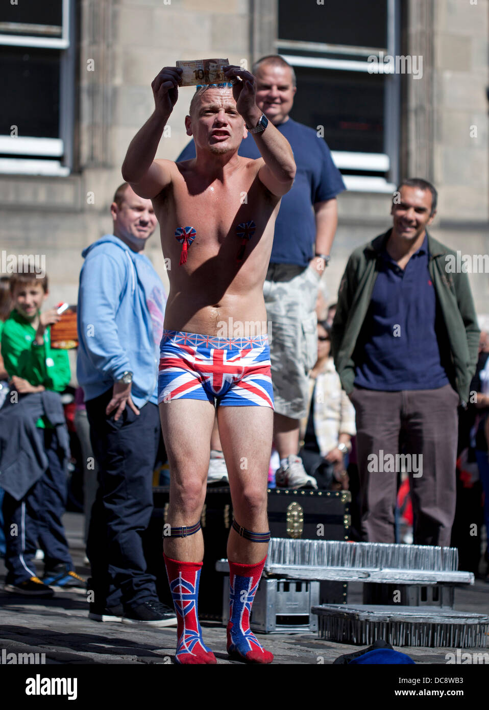 Edinburgh, Scotland, UK. 12th August 2013.  Fringe Street Performer 'Spiky Will' involves audience before demonstrating the donation he would like to receive, Royal Mile Stock Photo