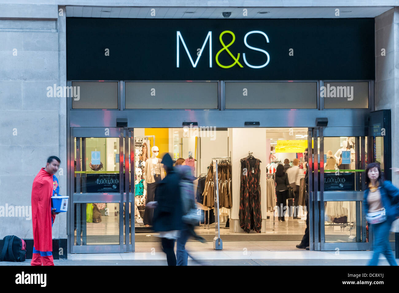 A beggar (maybe a fund-raiser?) in a superman suit outside a Marks and Spencer store. Stock Photo