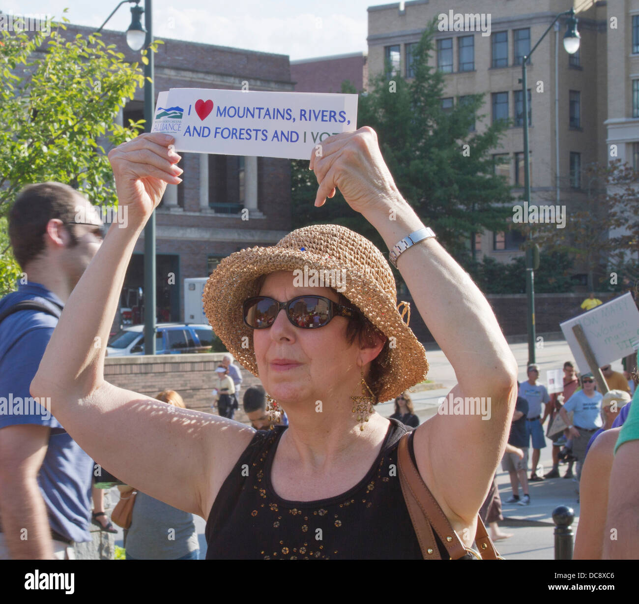 Older woman holds a pro environment sign that says she votes at the Moral Monday rally in downtown Asheville, North Carolina, US Stock Photo