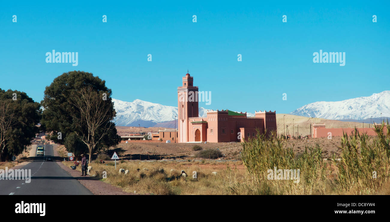 A road going by a temple with blue sky and the Atlas mountains; Souss-Massa-Draa, Morocco Stock Photo