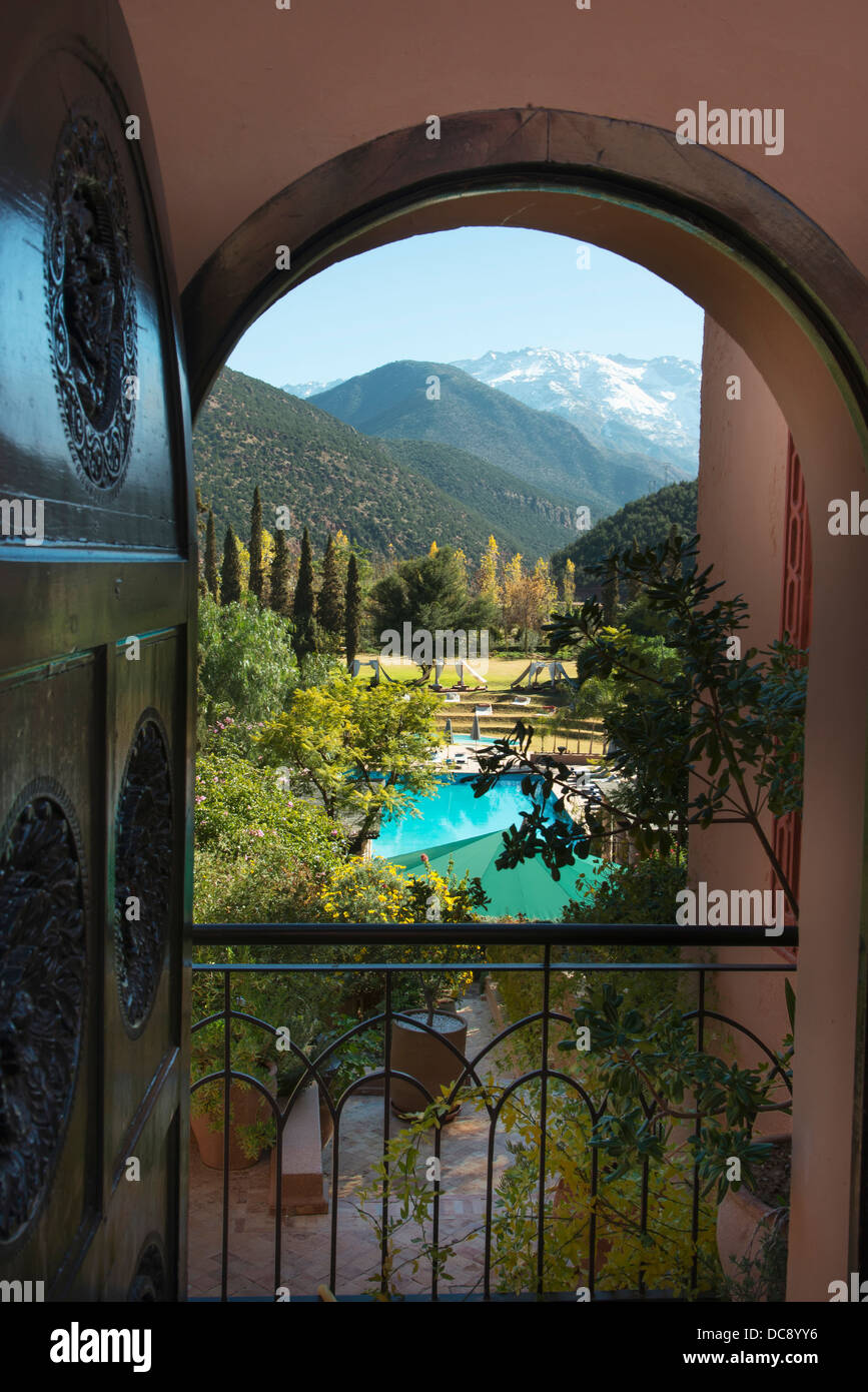 View Through An Arched Doorway To A Turquoise Pool Of Water And The Atlas Mountains In The Background; Morocco Stock Photo