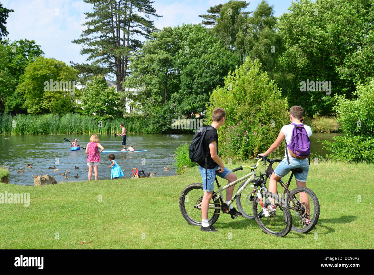 Boys on bicycles and children kayaking on River Thames, Pangbourne