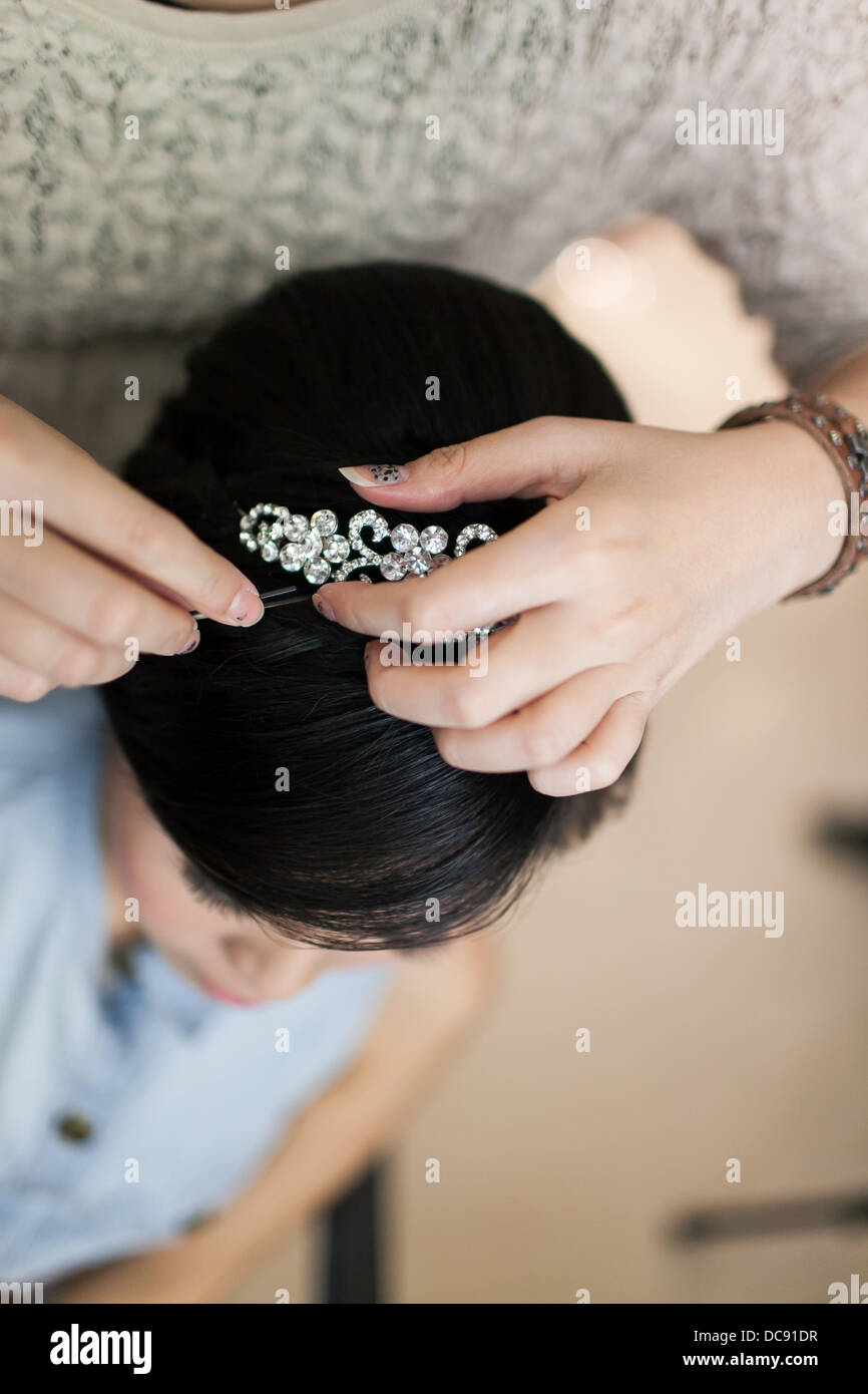 Hair stylist preparing a hair accessory on a woman's hair. Stock Photo