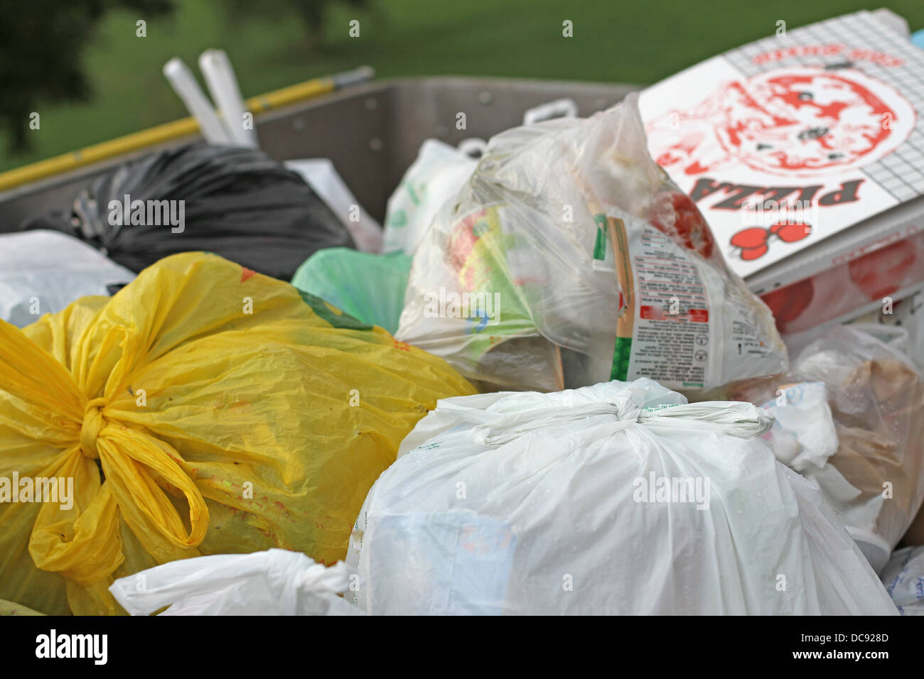 bags and trash into a dumpster full of garbage and solid waste Stock