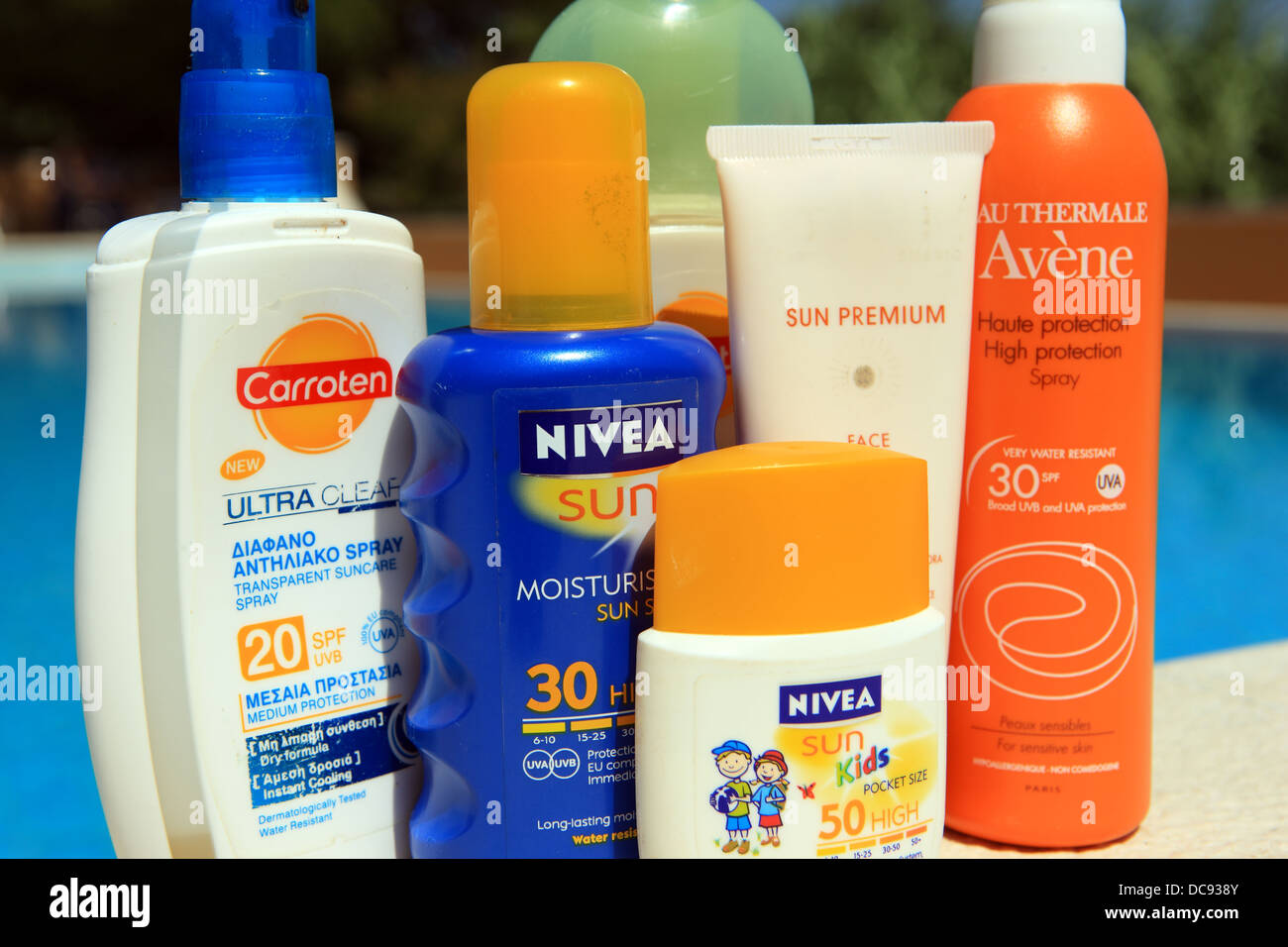 Sunscreen creams and lotions in the sun at the side of a swimming pool