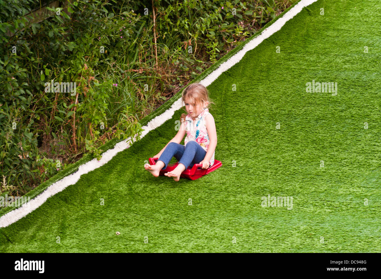 5 year old girl sliding down a hill Stock Photo