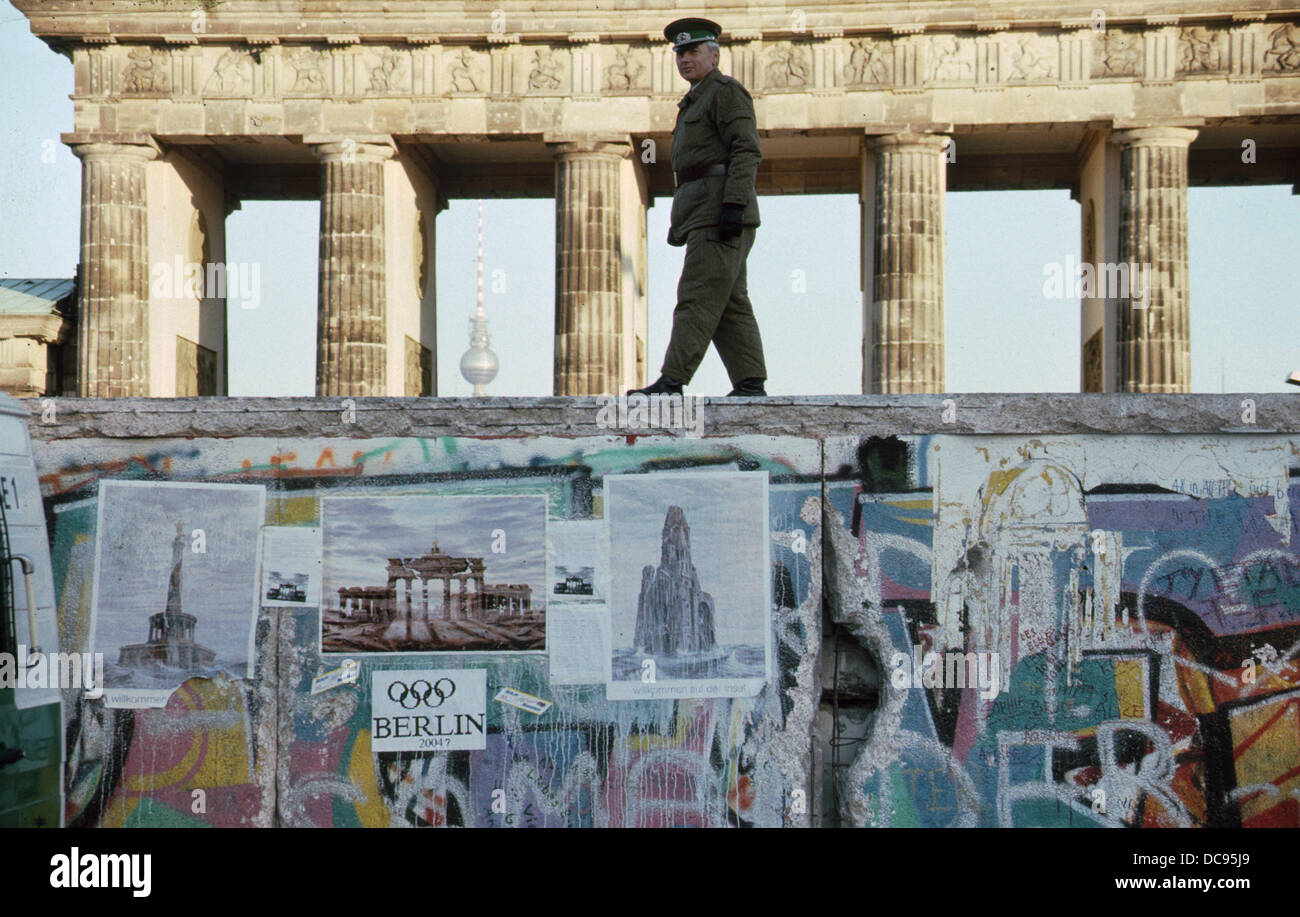 Opening of the Berlin Wall - East German NVA border guard is walking on top of the wall in the Western side of the separation barrier at the Brandenburg Gate, looking at the Western part of the city on NOvember 16th 1989. Photo: Sven Barten (c) dpa - Report Stock Photo