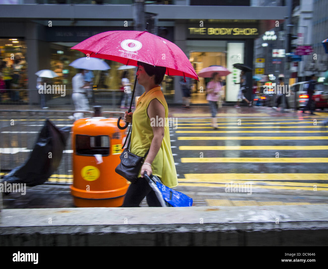 Hong Kong. 13th August 2013.  A woman walks up Queen's Road in Hong Kong while rain from Typhoon Utor hits the island. Typhoon Utor (known in the Philippines as Typhoon Labuyo) is an active tropical cyclone located over the South China Sea. The eleventh named storm and second typhoon of the 2013 typhoon season, Utor formed from a tropical depression on August 8. The depression was upgraded to Tropical Storm Utor the following day, and to typhoon intensity just a few hours afterwards. Credit:  ZUMA Press, Inc./Alamy Live News Stock Photo