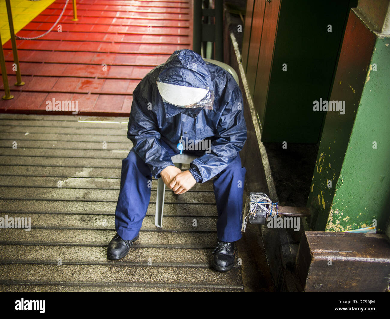 Hong Kong. 13th August 2013.  A Star Ferry worker takes shelter on a ferry gangway and waits out rains from Typhoon Utor in Hong Kong. Typhoon Utor (known in the Philippines as Typhoon Labuyo) is an active tropical cyclone located over the South China Sea. The eleventh named storm and second typhoon of the 2013 typhoon season, Utor formed from a tropical depression on August 8. The depression was upgraded to Tropical Storm Utor the following day, and to typhoon intensity just a few hours afterwards. Credit:  ZUMA Press, Inc./Alamy Live News Stock Photo