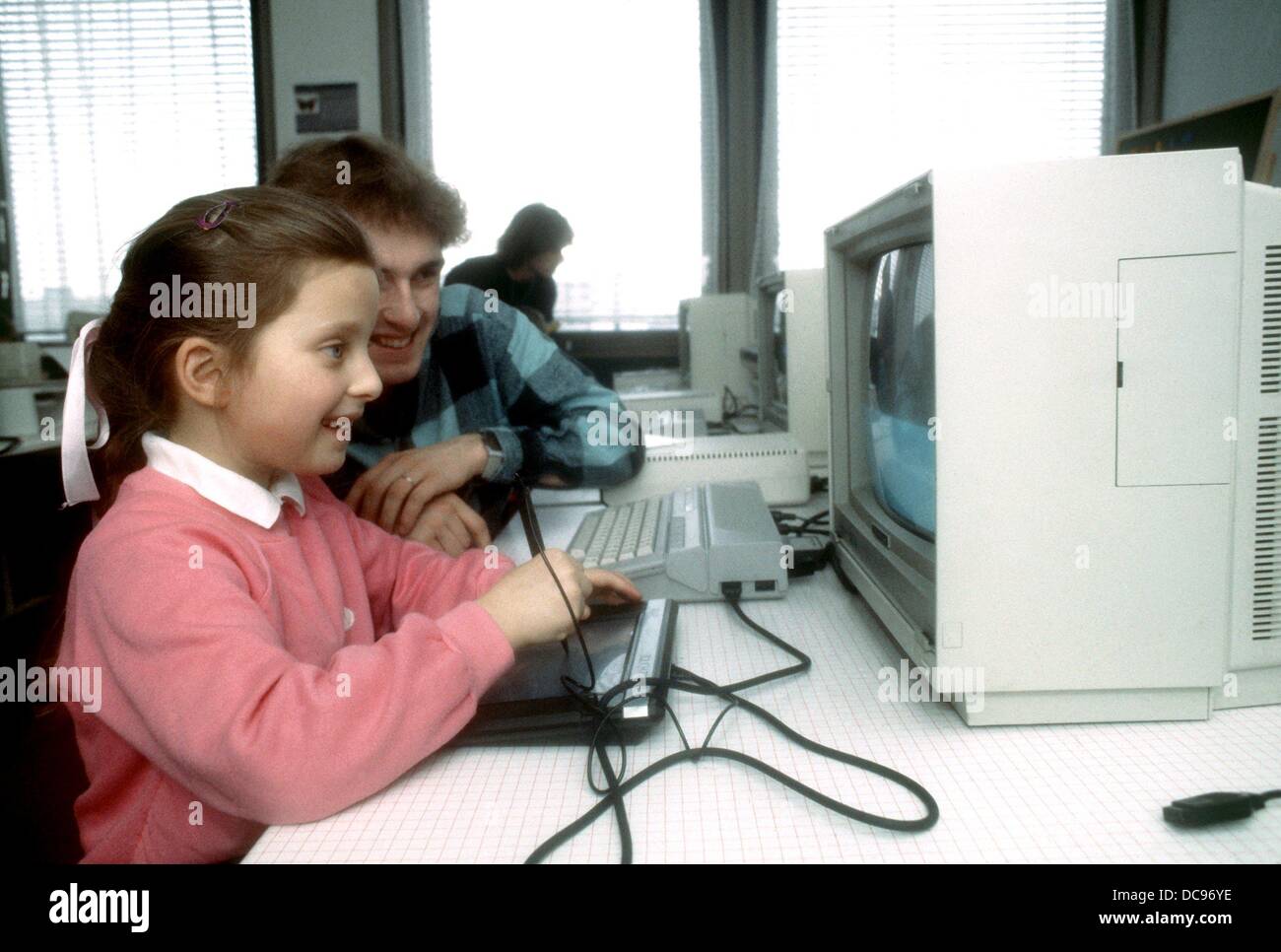 A girl of the so-called 'Basic babies' smiles in front of a monitor in the computer studio in Munich on the 6th of March in 1986. Stock Photo