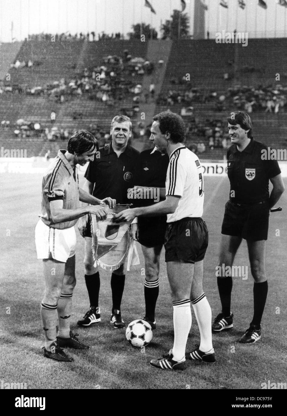 Johan Cruyff (l) and Franz Beckenbauer (2nd of right), the team leaders of the Dutch and German national team, exchange banners shortly before the match on the 3rd of July in 1984 in Munich. Stock Photo