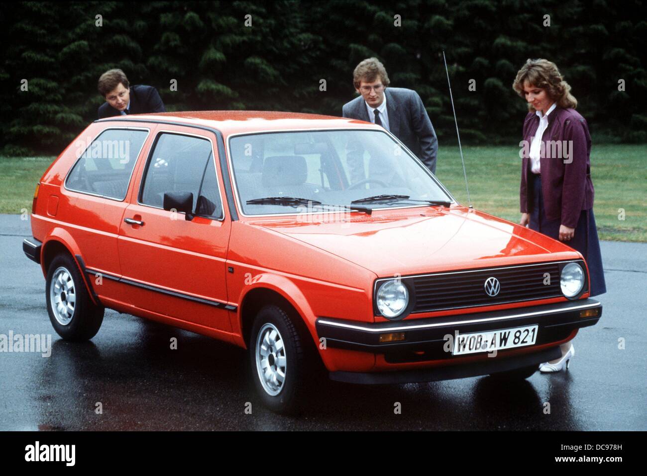 Two men and a woman have a look at a red VW Golf GL, photographed in 1983  Stock Photo - Alamy