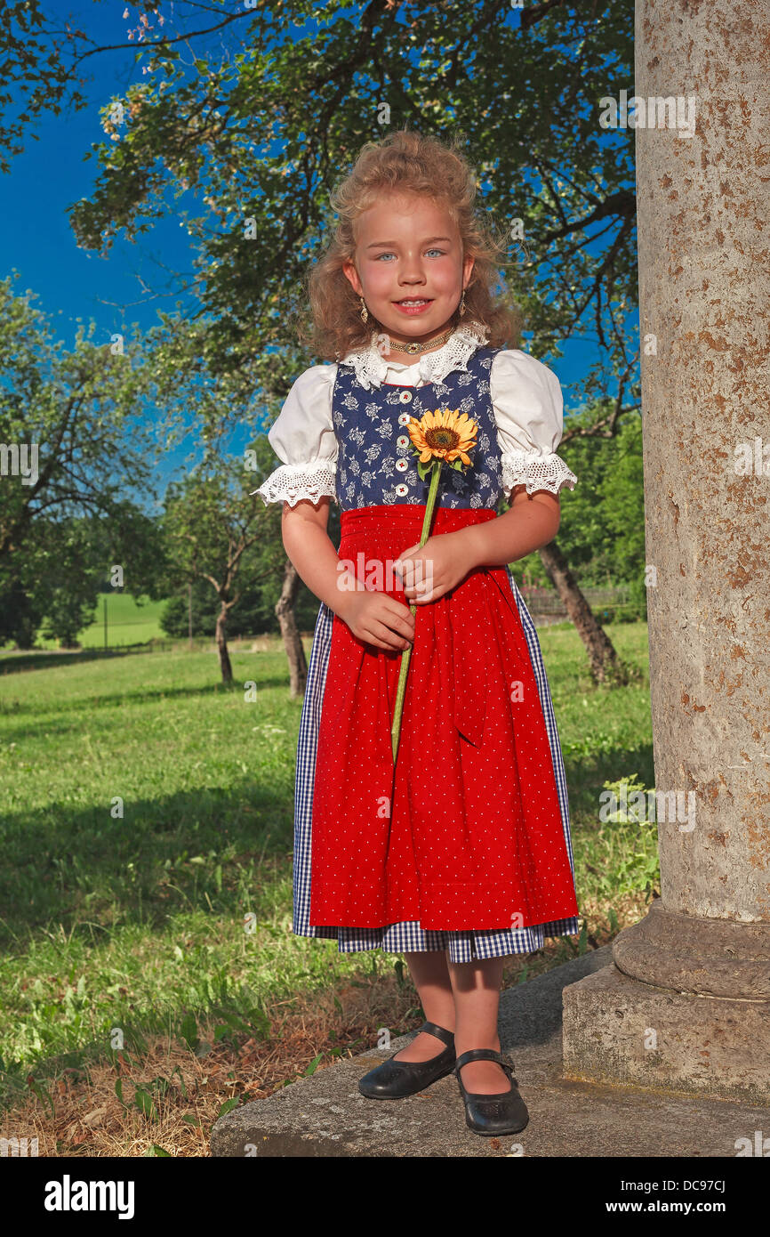 small Bavarian girl in a dirndl with sunflower Stock Photo