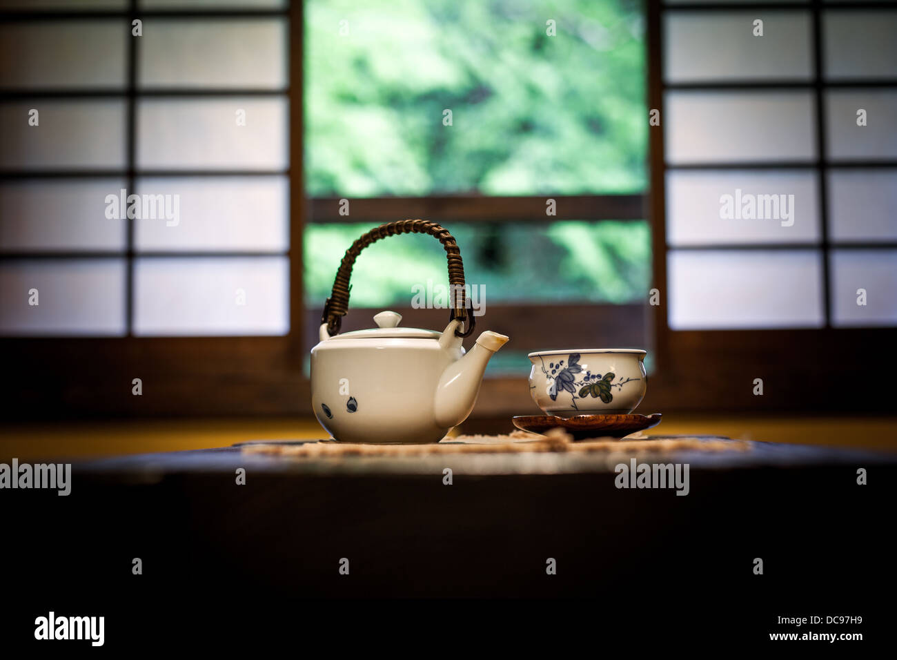 Teapot and tea bowl on a table in a traditional Japanese room in front of Shoji screen windows Stock Photo