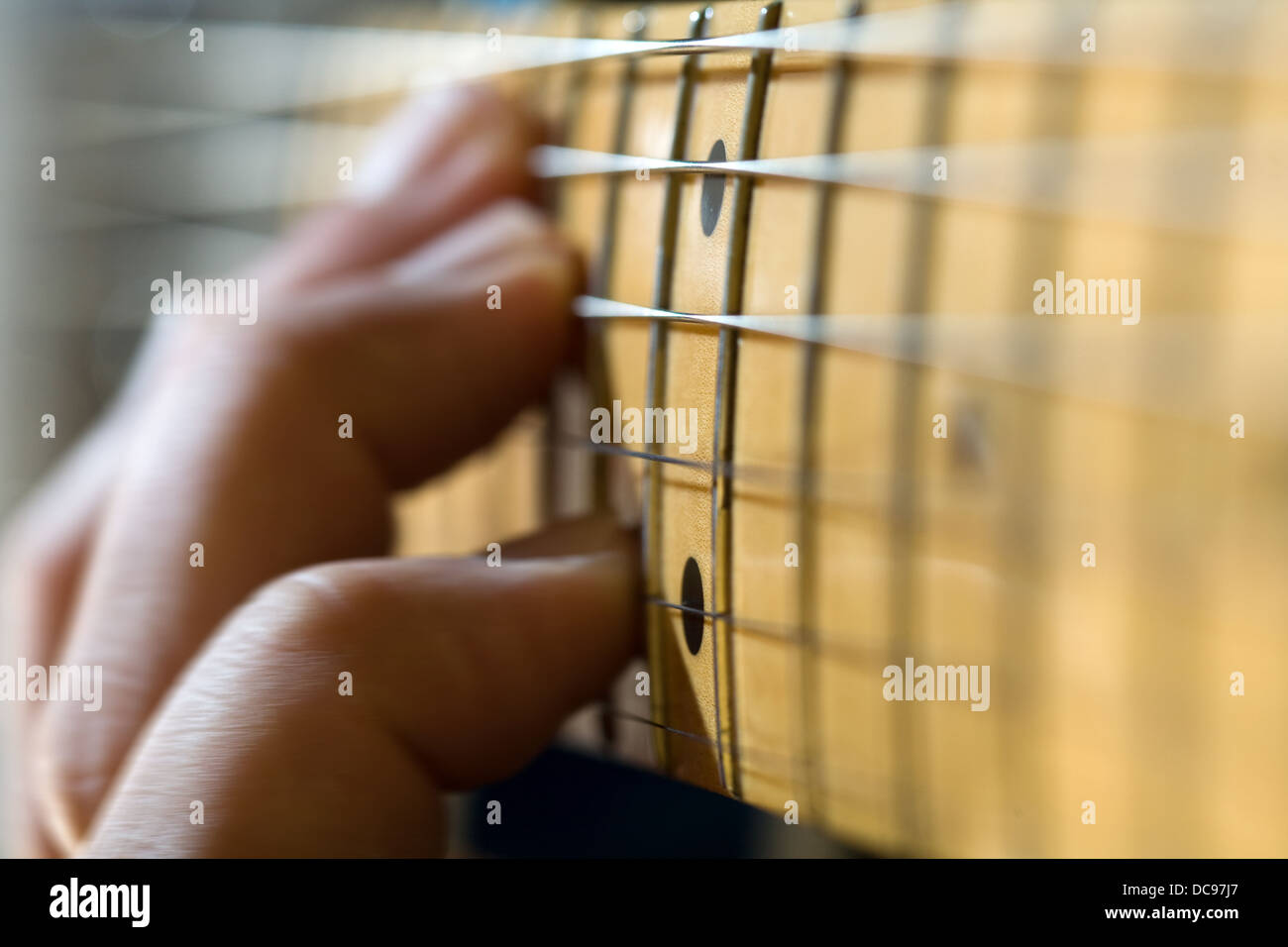 close-up of electric guitar fretboard with hand sliding a chord up the neck. Stock Photo