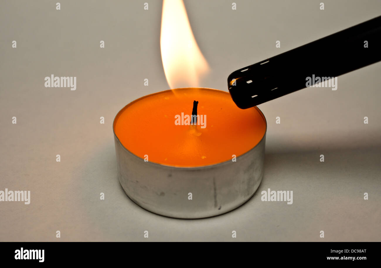 a tea light candle being lit on a white back ground Stock Photo Alamy