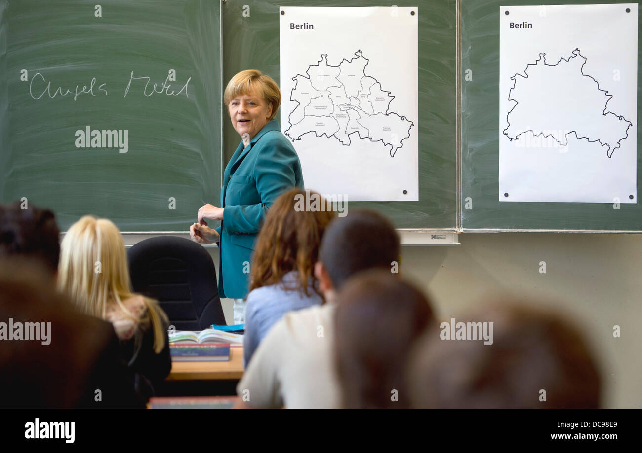 Berlin, Germany. 13th Aug, 2013. German Chancellor Angela Merkel writes her name on the black board and starts her lecture on the building of the Berlin wall August 13th,1961 to a 12th grade class during her visit to the Heinrich Schliemann Gymnasium, secondary school in Berlin, Germany on August 13, 2013. Photo: Odd Andersen dpa (c) dpa/Alamy Live News Stock Photo