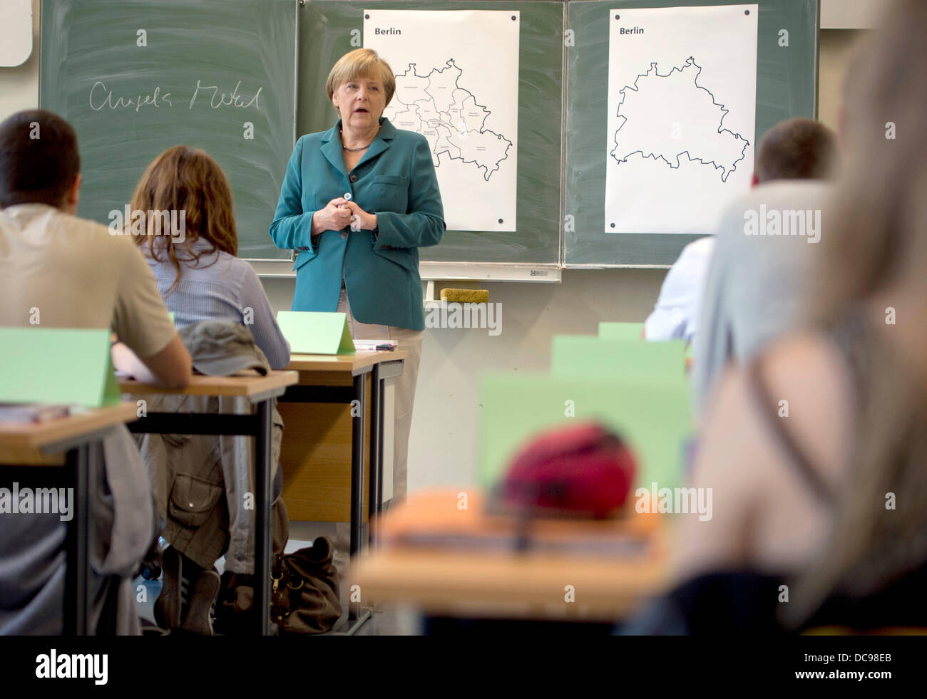 Berlin, Germany. 13th Aug, 2013. After writing her name on the black board (L) German Chancellor Angela Merkel starts her lecture on the building of the Berlin wall August 13th,1961 to a 12th grade class during her visit to the Heinrich Schliemann Gymnasium, secondary school in Berlin, Germany on August 13, 2013. Photo: Odd Andersen dpa (c) dpa/Alamy Live News Stock Photo