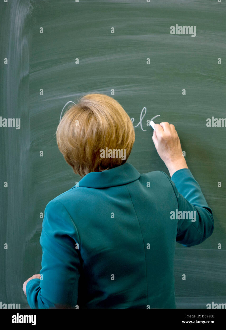 Berlin, Germany. 13th Aug, 2013. German Chancellor Angela Merkel writes her name on the black board before starting her lecture on the building of the Berlin wall August 13th,1961 to a 12th grade class during her visit to the Heinrich Schliemann Gymnasium, secondary school in Berlin, Germany on August 13, 2013. Photo: Odd Andersen dpa (c) dpa/Alamy Live News Stock Photo